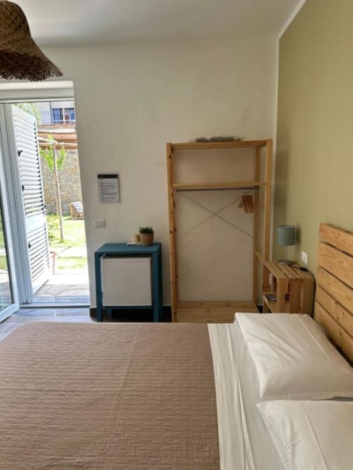 Camera Bright King a Cilento Rooms con vista giardino, armadio in legno, letto e accesso al patio ad Agnone