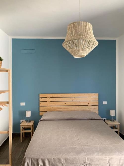 Camera moderna a Cilento Rooms con letto in legno, parete accent teal, lampada a sospensione intrecciata e comodini in legno