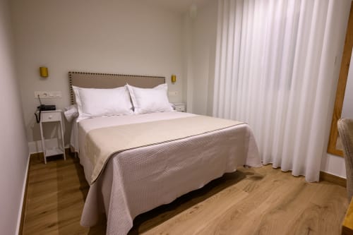 Dormitorio moderno con cabecero tapizado en beige, almohadas blancas y ropa de cama clara en Hotel Boutique Alcazaba en Salobreña,