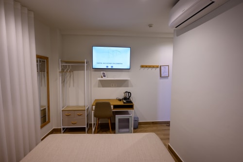 Habitación moderna del hotel Alcazaba Salobreña con cama, escritorio, armario, TV y aire acondicionado en Granada