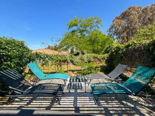 Terrasse ensoleillée avec transats turquoise et coin ombragé entouré de verdure à l'appartement L'Île-Rousse