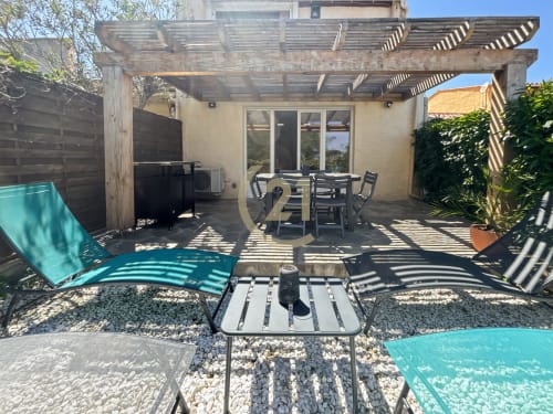 Spacious terrace with dining area, lounge chairs, and pergola overlooking sea view in L'Île-Rousse apartment