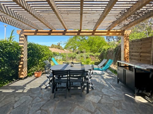 Terrasse avec pergola ombragée, table à manger, chaises longues et barbecue à l'Île-Rousse près de la mer