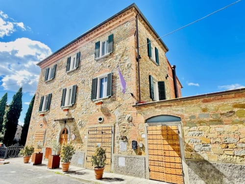 Historic stone building at Agriturismo CasaVa in Pozzo della Chiana, Italy with terracotta doors and cypress trees