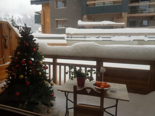 Balcon enneigé à Zoppas Courchevel avec sapin de Noël décoré, mobilier extérieur et vue sur les montagnes de ski