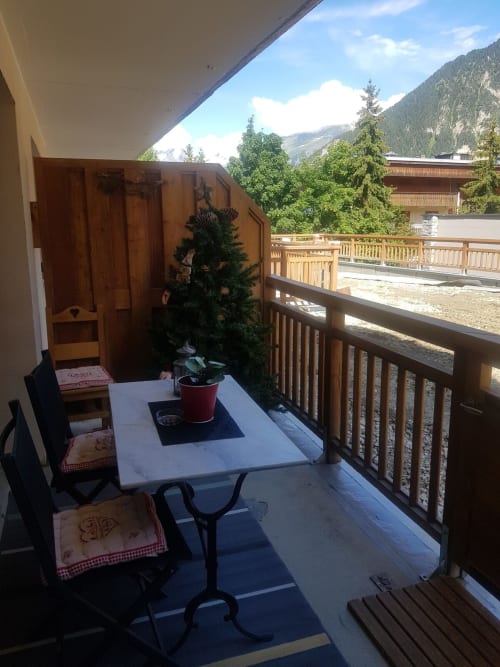 Balcon cosy de Zoppas Courchevel avec vue sur les montagnes, table à manger, chaises et plante en pot surplombant la station de ski