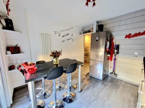 Cuisine moderne avec table de salle à manger noire, électroménagers en acier inoxydable et armoires blanches à l'appartement Zoppas Aix-les-Bains.