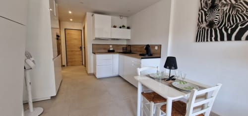 Cuisine et salle à manger modernes à Zoppas Aix Les Bains : mobilier blanc, plan de travail foncé, table et zèbre