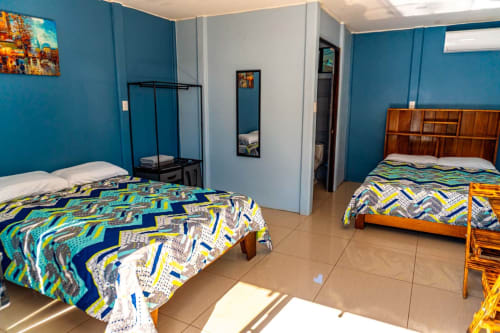 Habitación luminosa y espaciosa en Cabinas Arenal Home con dos camas, paredes azules y muebles de madera en La Fortuna, Costa Rica