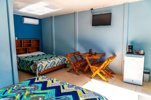Habitación colorida en Cabinas Arenal Home en La Fortuna con cama, muebles de madera, aire acondicionado y TV
