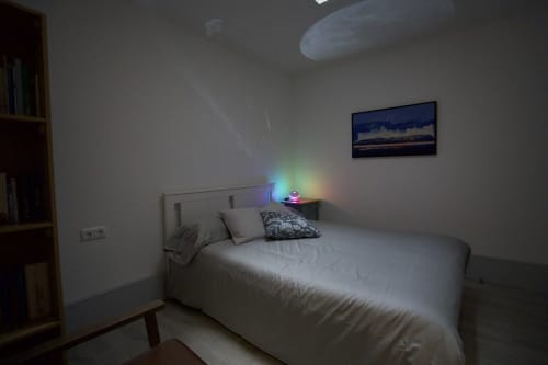 Quarto moderno na Pousada Boutique Santiago de Caminha com cama queen, iluminação ambiente, prateleiras de madeira e obras de arte emolduradas