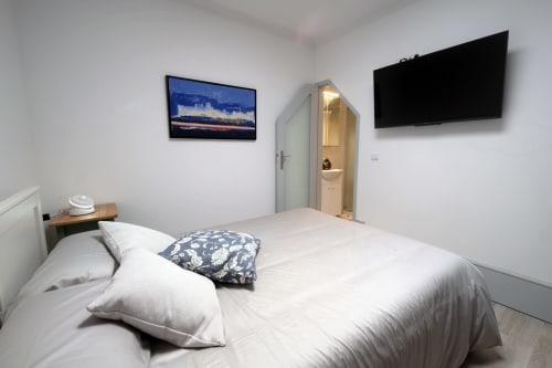 Quarto moderno na Santiago de Caminha Boutique Hostel com roupa de cama branca, TV e banheiro privativo em Caminha, Portugal