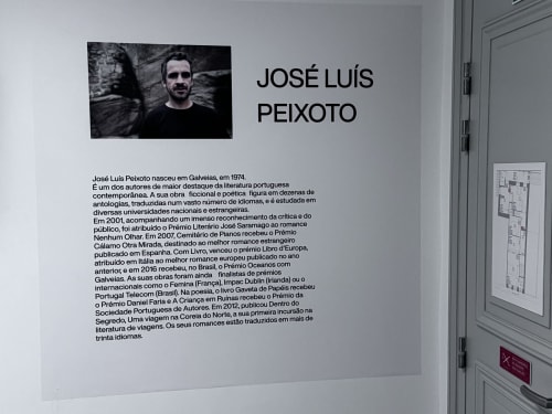 Biografia de José Luís Peixoto exibida no quarto 102 do Santiago de Caminha Boutique Hostel, retrato do autor português e acervo literário