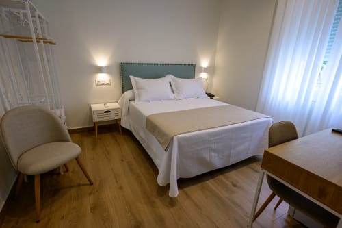 Luminosa habitación de hotel con cama queen, cabecero verde, suelo de madera, mobiliario moderno y vistas al jardín en Alcazaba Salobreña