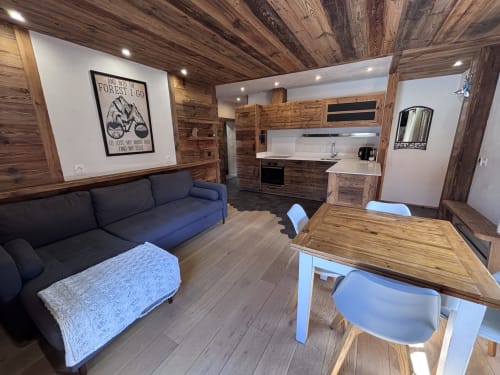Modern cabin interior at Chez Francine with wooden ceilings, navy sofa, dining table, and kitchenette in Notre Dame de