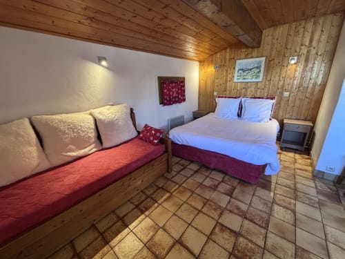 Chambre chaleureuse en bois chez Francine avec lit double, petit lit et carrelage en terre cuite rustique