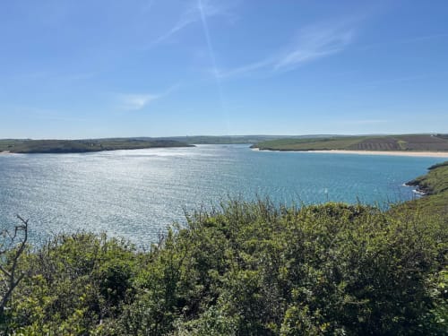Turquoise coastal bay with green cliffs and farmland, scenic view near Exeter holiday property