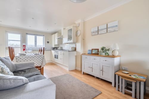 Open-plan kitchen and living area at 2 Doves Holiday Property in Exeter with cream cabinetry, wooden flooring, and coastal