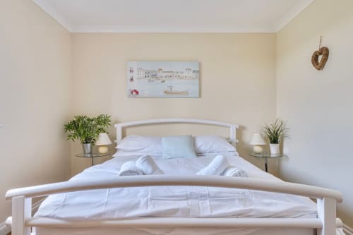 Bright, modern bedroom at 2 Doves Holiday Property in Exeter with white bed, fresh linens, plants, and coastal artwork