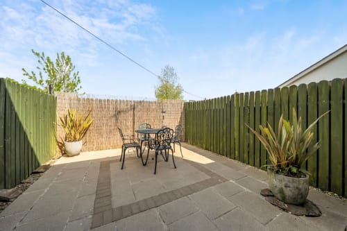 Enclosed patio at 2 Doves Holiday Property in Exeter with dining table, green fencing, and potted plants