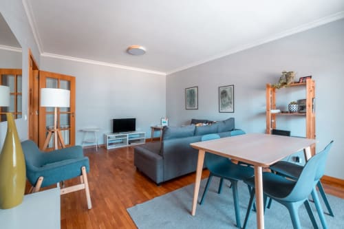Apartamento moderno com vista para o mar no EcoHost Perafita com mesa de jantar, sofá azul, móveis de madeira e cozinha equipada para 4 pessoas