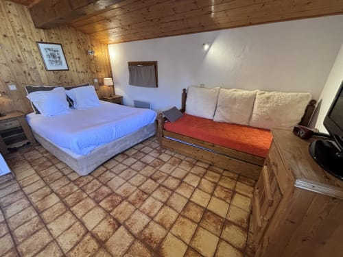 Chambre rustique à Chez Francine : lit queen-size, lit de repos et carrelage en terre cuite à Notre Dame de Bellecombe