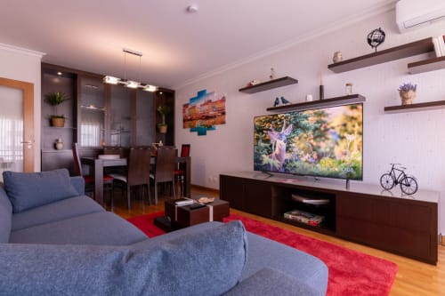 Sala de estar moderna no apartamento OceanBreeze da EcoHost Perafita com sofás azuis, TV de tela plana e móvel escuro