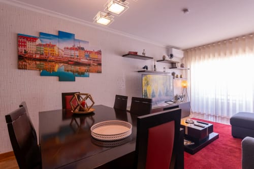Sala de estar moderna com mesa de jantar, tapete vermelho, obra de arte marítima e decoração costeira no EcoHost Perafita