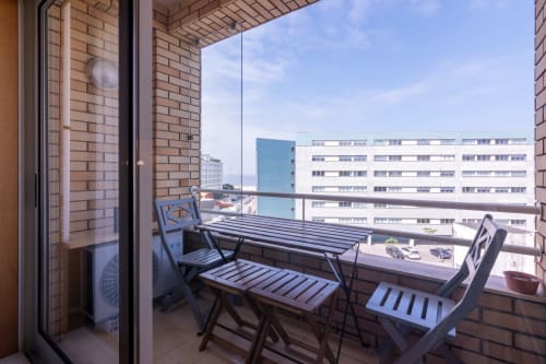 Varanda com mesa de jantar e cadeiras com vista para edifícios à beira-mar em Perafita