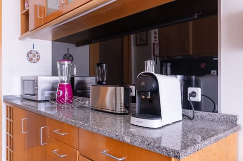 Cozinha moderna no apartamento OceanBreeze da EcoHost Portugal com eletrodomésticos de aço inoxidável e bancada de granito