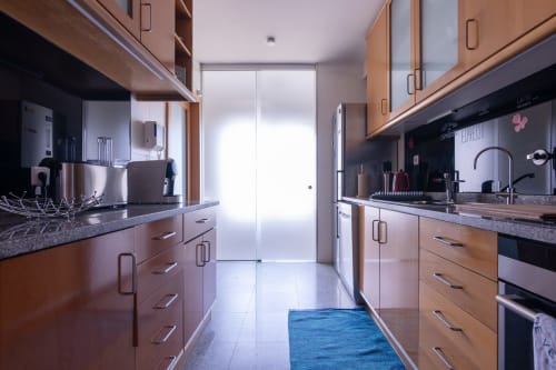 Cozinha moderna no apartamento OceanBreeze da EcoHost, Perafita, com armários em madeira, bancadas em granito e aço inoxidável