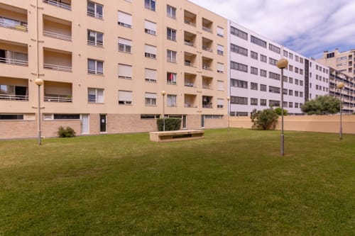 Espaçoso pátio verde do edifício de apartamentos EcoHost em Perafita com unidades residenciais modernas e luminárias