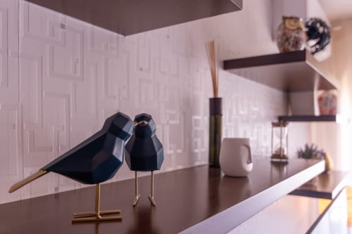 Decoração moderna no EcoHost Perafita com estatuetas de pássaros pretos sobre mesa escura, paredes roxas e prateleiras flutuantes