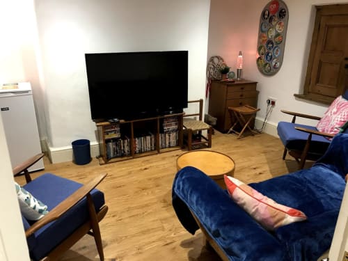 Cozy living room at 2 Doves Holiday Property in Exeter with blue seating, TV, wooden furniture and decorative plates