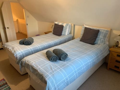 Two twin beds with blue checkered bedding and rolled towels at 2 Doves Holiday Property in Exeter