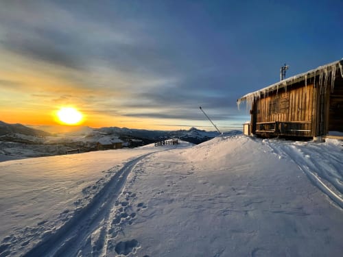 Snow-covered mountain cabin at sunset near Chez Francine, Notre Dame de Bellecombe, French Alps