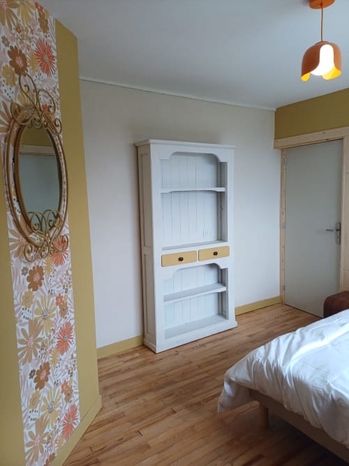 Bright bedroom at La Maison de Dun B&B in Saint Racho with white shelving, floral wallpaper, and wooden flooring