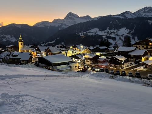 Snowy alpine village Chez Francine at dusk in Notre Dame de Bellecombe, mountains backdrop