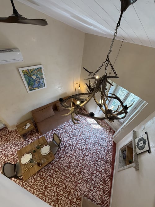 Blick vom oberen Stockwerk in das Wohnzimmer des okzitanischen Heritage-Ferienstudios in La Sarrasine, Aiguèze: Geweihleuchter, gemusterte Fliesen und Blick auf die historische Stadt, mit Flusszugang nur 3 Gehminuten entfernt.