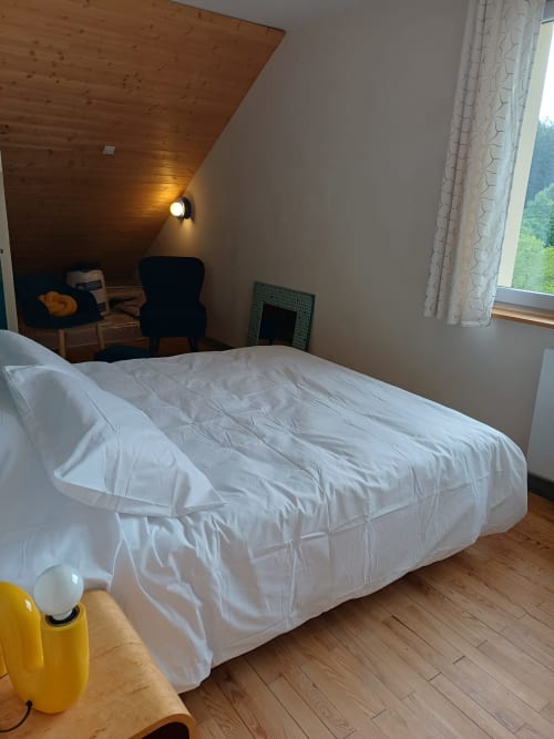 Cozy bedroom at La Maison de Dun B&B in Saint Racho with white bedding, wooden ceiling, and window view