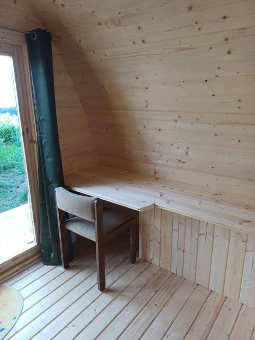 Wooden pod interior at La Maison de Dun with desk, chair, and mountain views through open door in Saint Racho