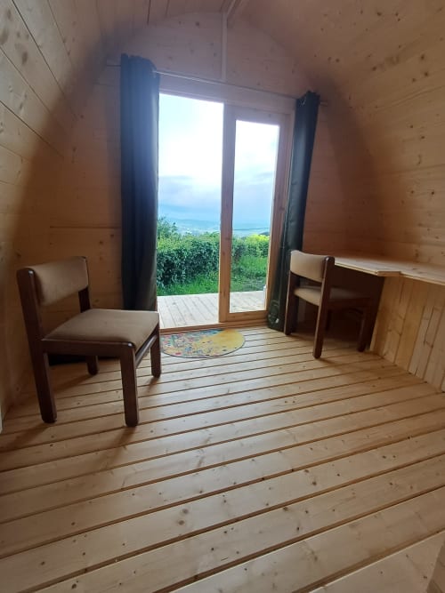 Wooden pod room with mountain view, two chairs, glass doors opening to landscape at La Maison de Dun, Saint Racho