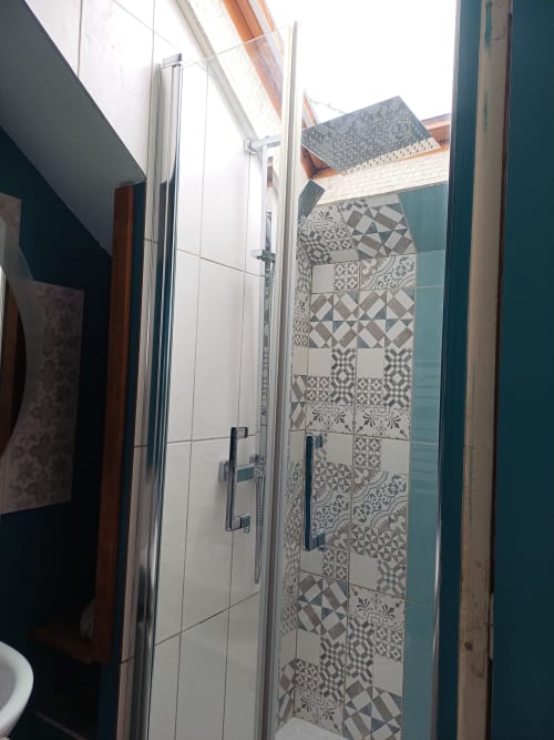 Modern shower enclosure with decorative patterned tiles at La Maison de Dun B&B in Saint Racho, France