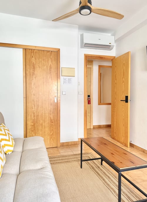 Chambre moderne à Nanit Rooms Ibiza avec portes en bois, ventilateur de plafond, climatisation et mobilier contemporain