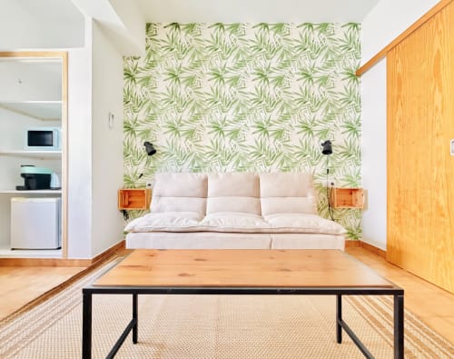 Chambre moderne à Nanit Rooms Ibiza avec canapé crème, papier peint botanique vert et mobilier minimaliste