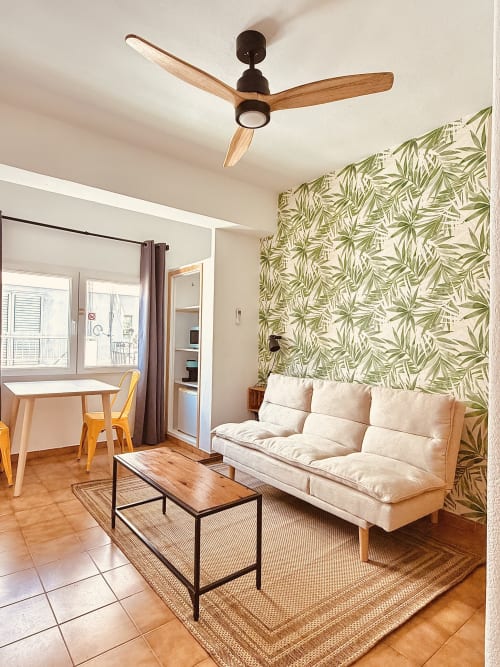 Chambre double confortable à l'auberge Nanit Rooms Ibiza avec canapé crème, ventilateur au plafond, papier peint tropical et mobilier moderne