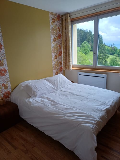 Cozy bedroom with white bedding, yellow walls, and scenic mountain views at La Maison de Dun B&B in Saint Racho