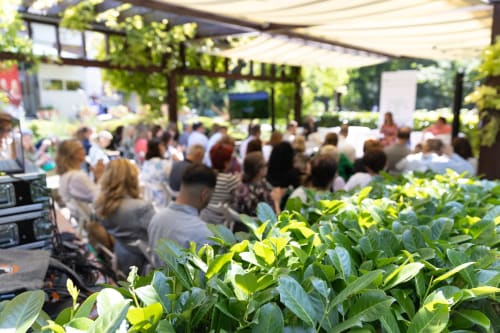 Réunion en plein air au jardin de la Chambre d'hôtes Domaine Alga à Bourg-Charente, avec plantes luxuriantes et pergola ombragée
