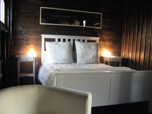 Chambre douillette aux Troglos de Beaulieu avec lit blanc, ambiance chaleureuse, murs en bois et rideaux avec vue sur le jardin