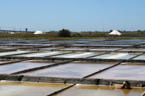 Salinas e bacias de evaporação em Aveiro, Portugal com estruturas industriais e montes de sal branco ao fundo